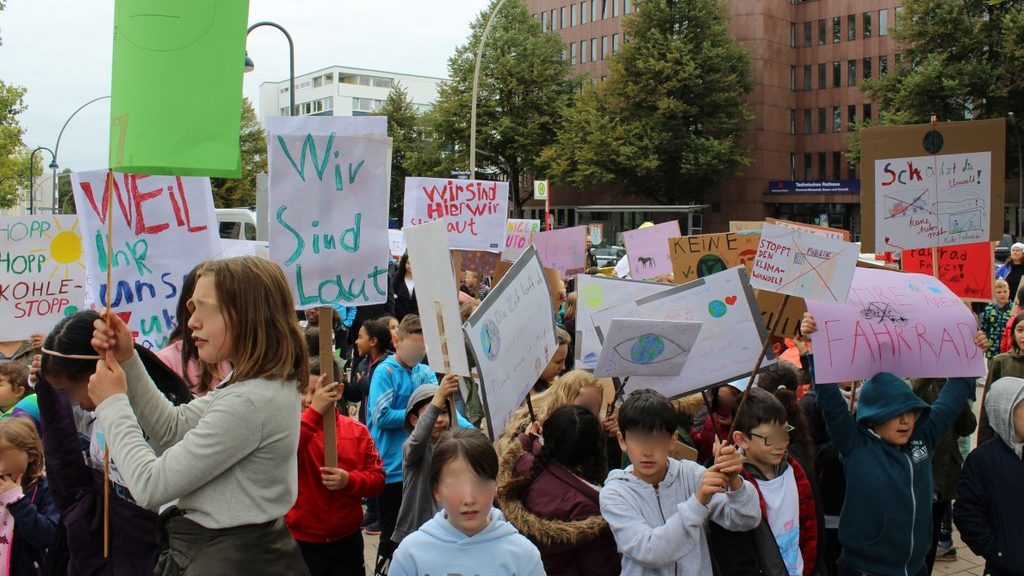Eine große Gruppe Kinder steht mit Plakaten auf einem Platz.