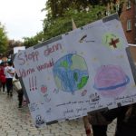 Ein Plakat zeigt Planeten. In großen Buchstaben steht da: "Stoppt den Klimawandel!"